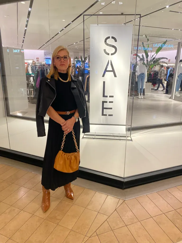 Julie standing in front of a Sale sign by a retail store